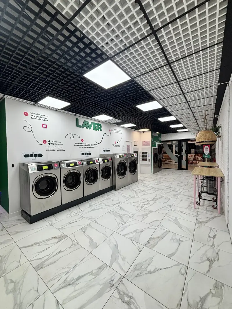 Laveuses alignées sous le mur vert